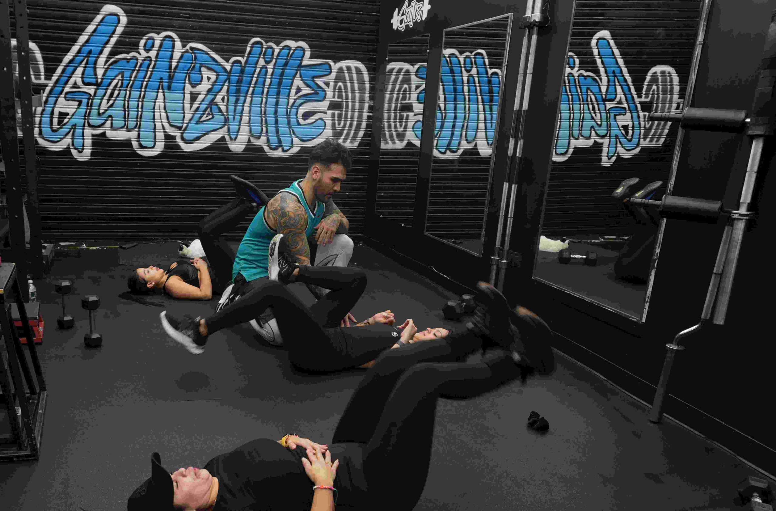 Coach guiding clients through floor work at the Gainzville NYC studio in Corona, Queens